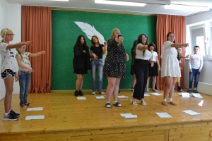 uczniowie na scenie czytają śpiewają i tańczą