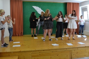 uczniowie na scenie czytają śpiewają i tańczą