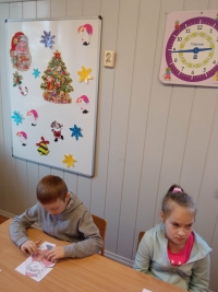 Uczniowie przy stolikach układają puzzle, rozwiązują rebusy. Ubierają się w ozdoby.